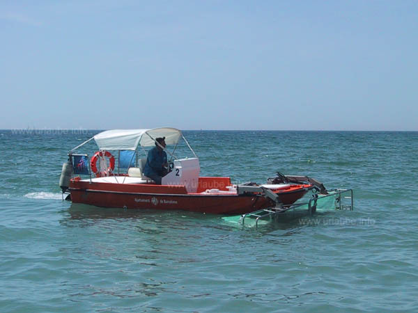 A boat with big grates that releases the water in the proximity of the beach from junk