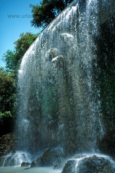 A small waterfall at medium height, under which many have a refreshing shower.