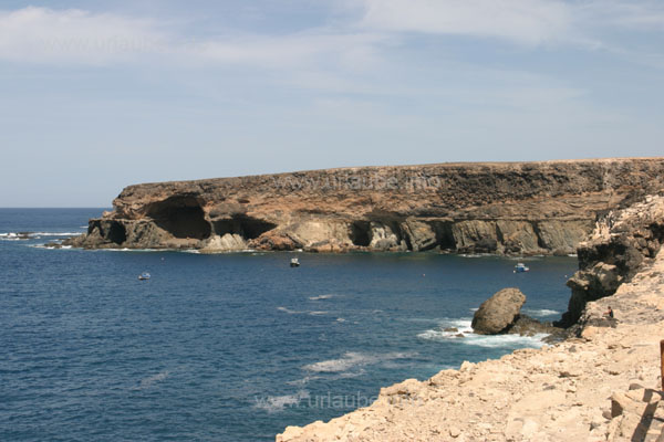 View to the bay Caleta Negra with the dark rock faces and caves