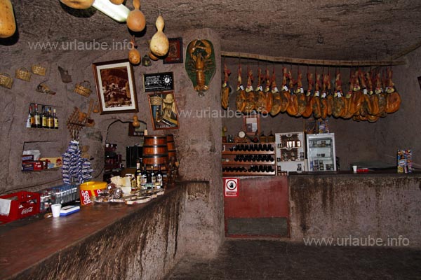 The cave bar appears very rusty due to its dark interior and the hams hanging from the ceiling.