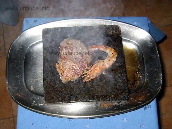 Preparation of a fillet of beef and a prawm on a hot stone right at the table
