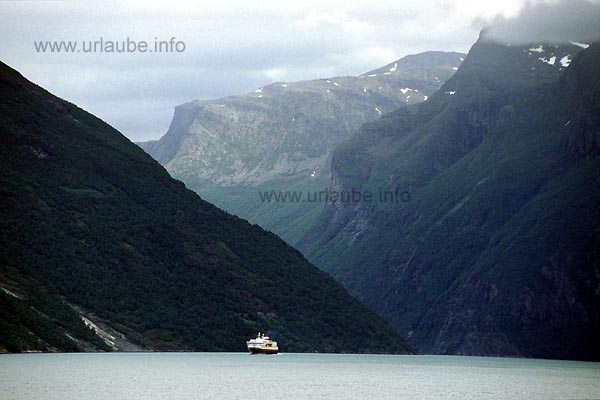 From board of the car ferry Hellesylt-Geiranger the view goes to the Sunnylfs fjord. There, the Hurtigrute MS Nordlys approaches coming from Alesund, in the shade of the mountains heighted more than 1500 metres, on its way to Geiranger.