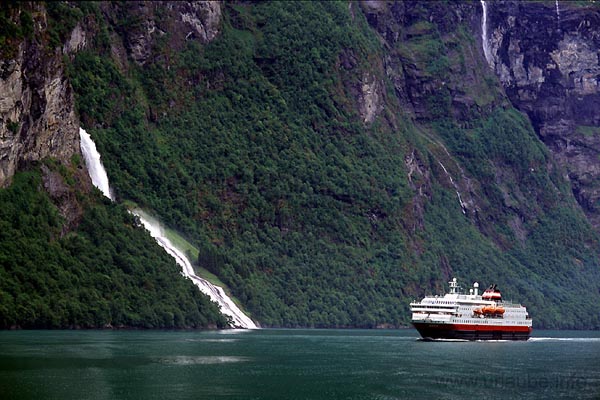 Meanwhile, swung in in the Geiranger fjord, the HUrtigrute passes the waterfall Friaren. Shortly after, the fast steamboat gets ahead of the car ferry by greeting with the hooter.