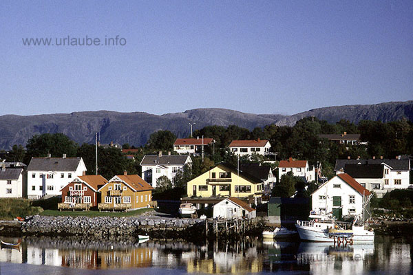 Colourful houses in front of the background of S&ouml;mnafjell accompany the exit of the Hurtigrute in Br&ouml;nn&ouml;ysund.